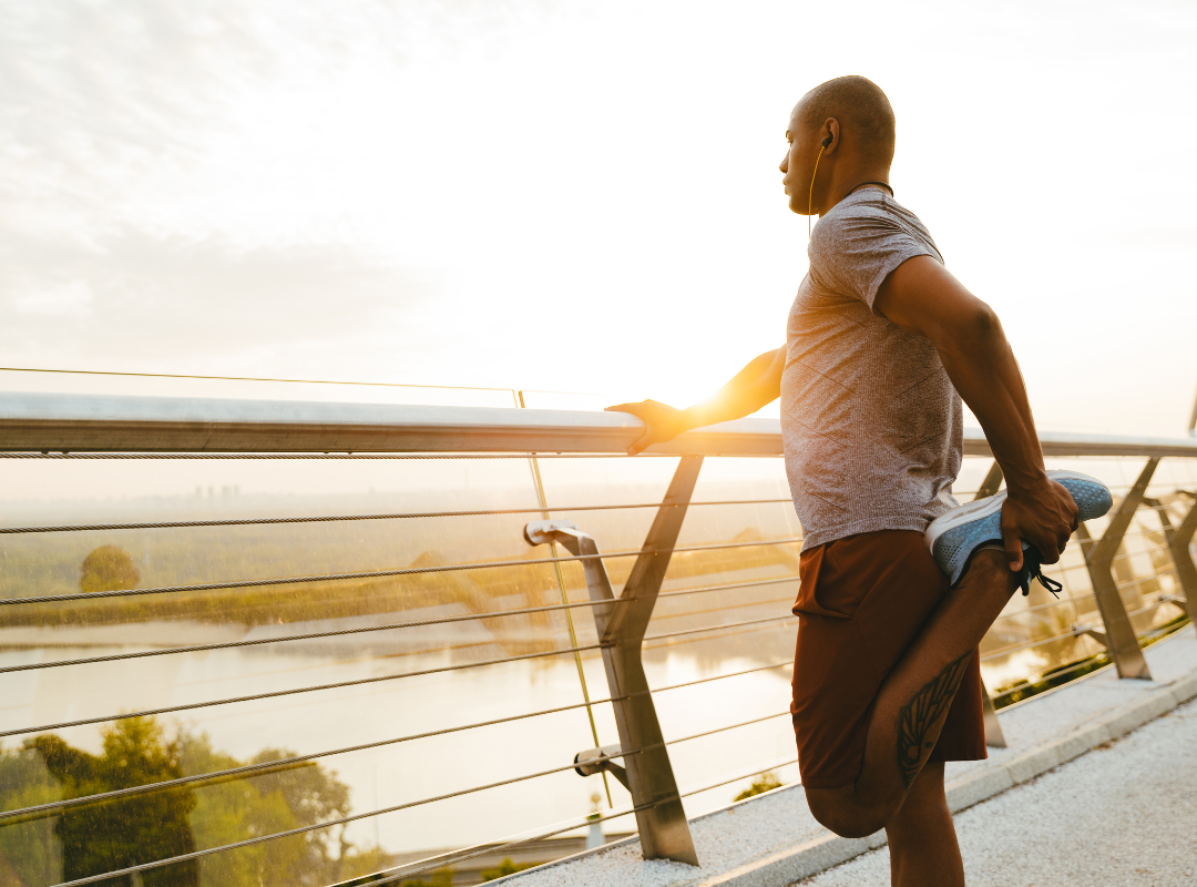 Man stretching on a bridge at sunrise, symbolizing the integration of training, recovery, and endurance strategies.