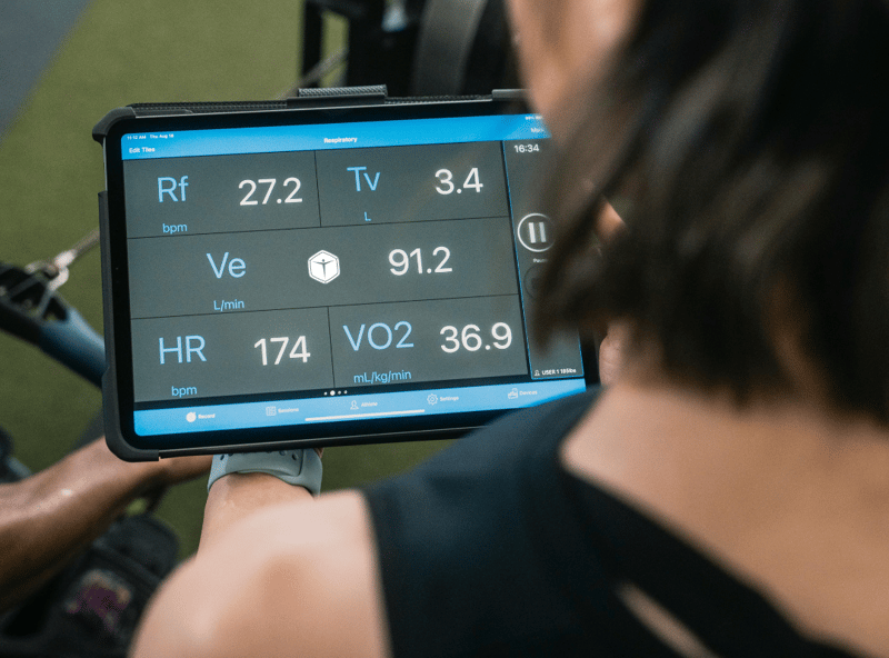 Athlete monitoring VO₂ max and heart rate data on a tablet during exercise.